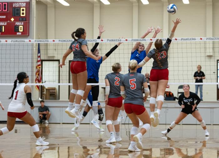 WCJC volleyball players leap high for the ball. 